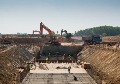 A close shot of heavy machines and construction workers working on a building