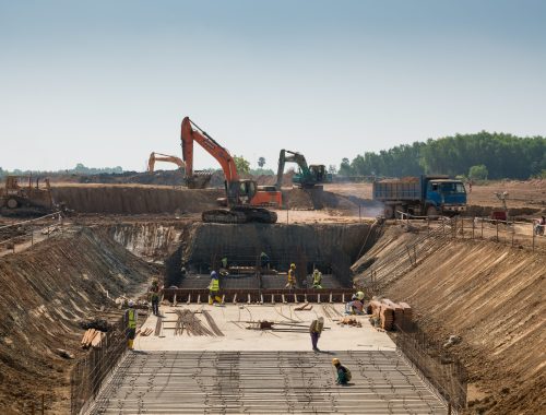 A close shot of heavy machines and construction workers working on a building